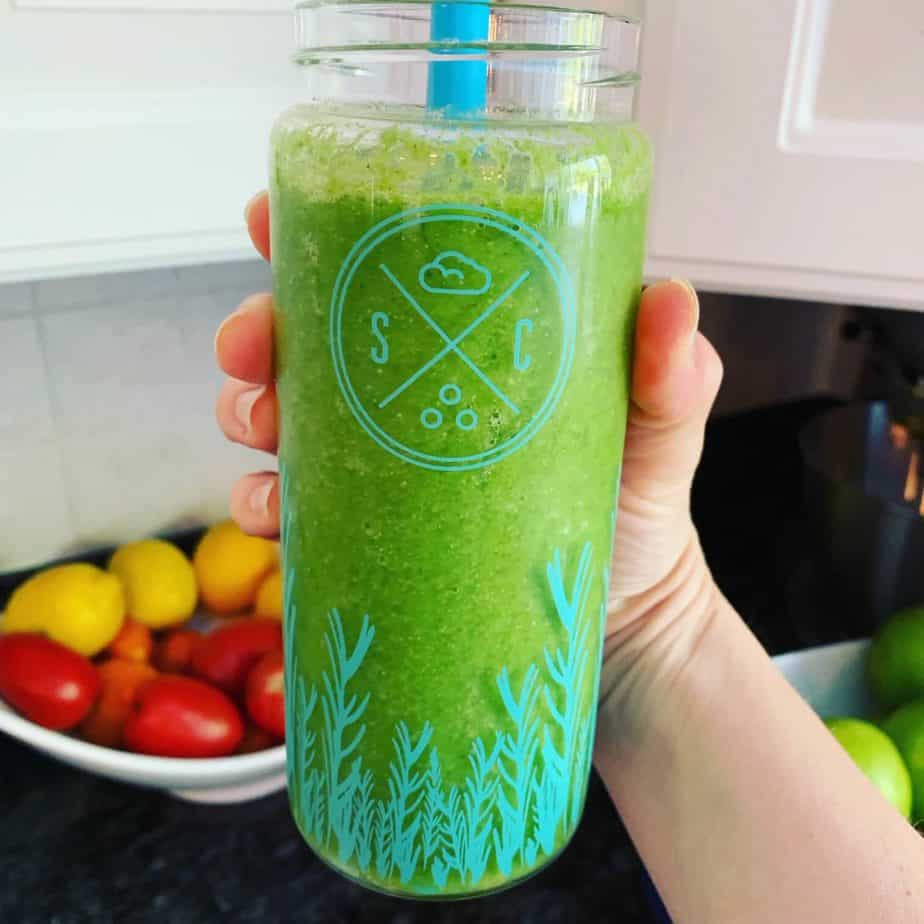 a hand holding a green smoothie